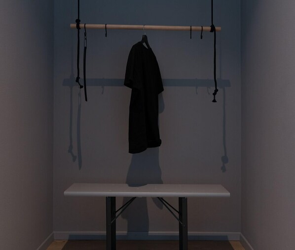 A room with a white table and a black coat hanging on a rod. - Luis von Weyden (Weiden am See)