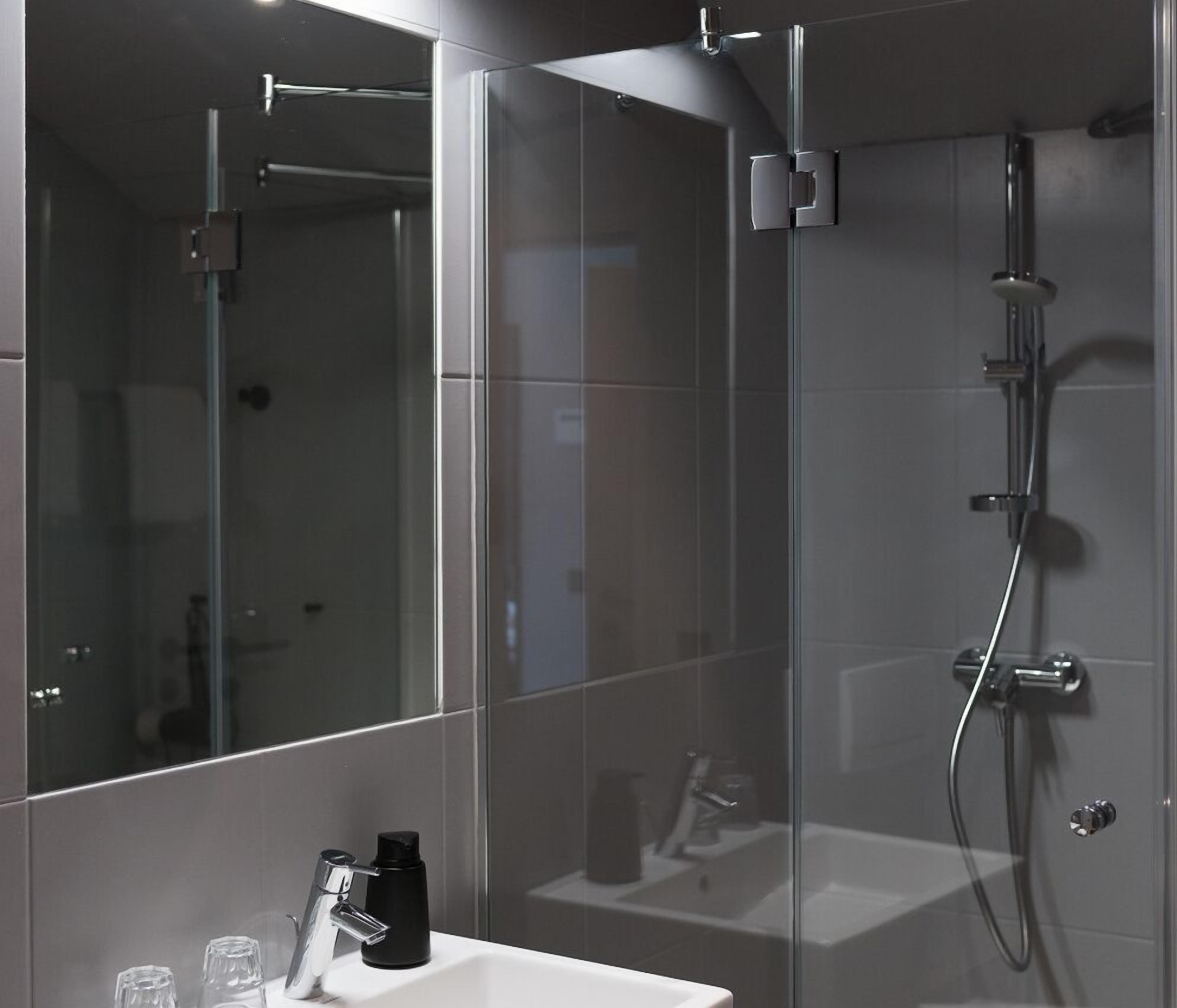 Un baño moderno con cabina de ducha de vidrio, lavabo blanco y espejo.
