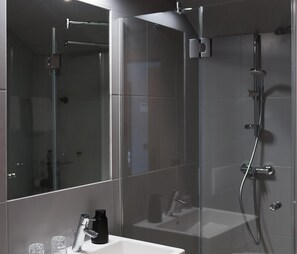 A modern bathroom with a glass shower enclosure, a white sink, and a mirror. - Luis von Weyden (Weiden am See)