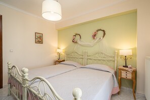 A bedroom with a double bed, two bedside tables, a wall-mounted light fixture, and a decorative wreath on the wall. - AIGLI ELEGANT SEA VIEW APARTMENT IN ARGOSTOLI (Αργοστόλι)