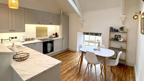 Una cocina moderna con armarios blancos, una mesa de comedor de madera y un tragaluz.