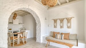 Un salon chaleureux avec une arche en pierre, un banc en bois, un canapé avec des coussins et une décoration murale en macramé.
