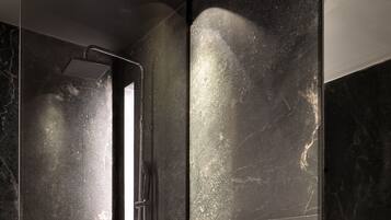 A modern bathroom with a large mirror, a shower, and a sink.