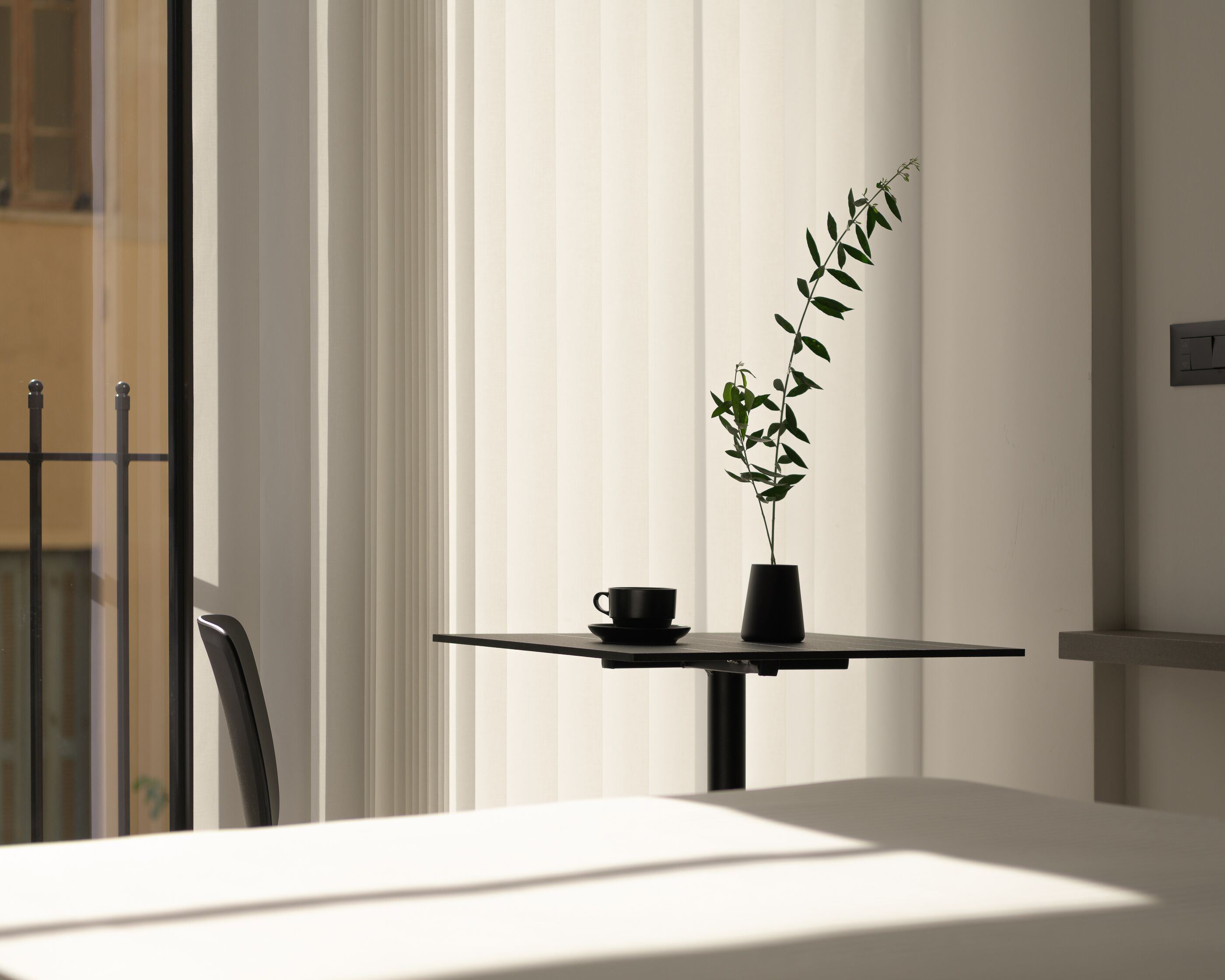 Una habitación moderna con una mesa, una planta en maceta y una taza.