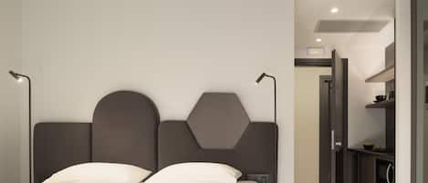 A modern bedroom with a large bed, a headboard with geometric shapes, and a bedside table with a lamp.