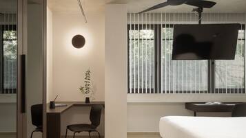 Une chambre moderne avec un lit, un bureau, une chaise, un téléviseur et un ventilateur de plafond.