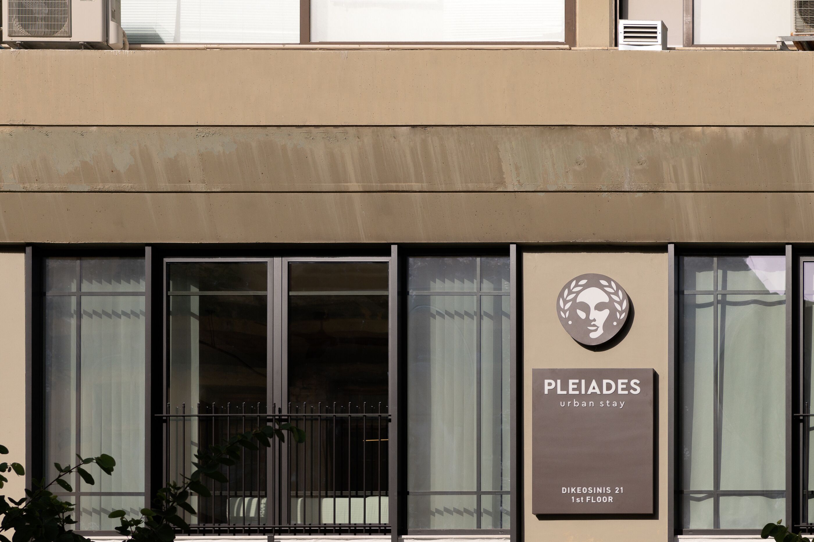A building with a sign that reads "PLEIADES urban stay" and "BIKEOSINIS 21 1st FLOOR".