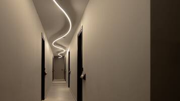 A hallway with a modern light installation curving along the ceiling.