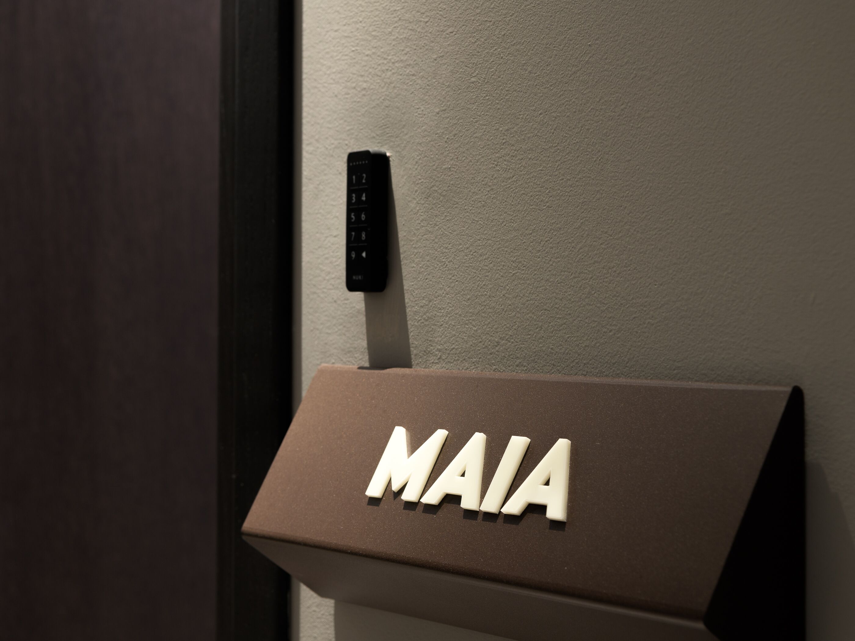 A door with a keypad and a sign with the letters "MAIA".