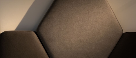 A modern bed with a geometric headboard and a neatly made white sheet.