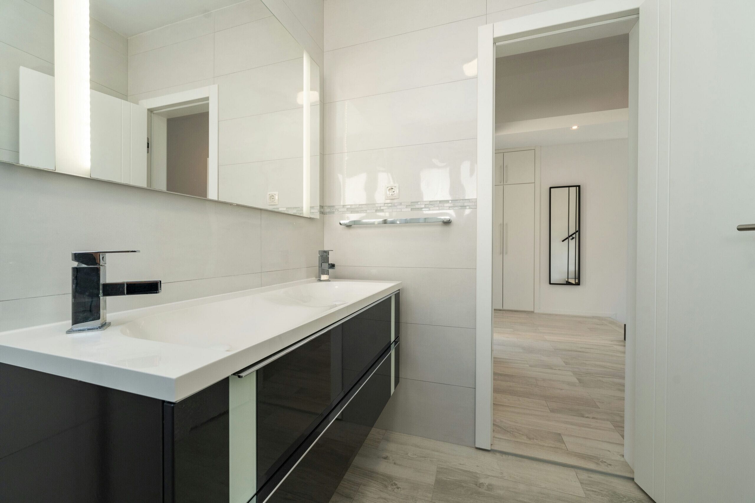 A modern bathroom with a white vanity, a large mirror, and a walk-in shower.