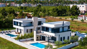 A modern two-story house with a swimming pool, surrounded by greenery and a view of distant mountains. - Villa Marita (Privlaka)