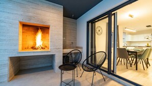 A modern living area with a fireplace, two black chairs, and a dining area visible through glass doors. - Villa Marita (Privlaka)