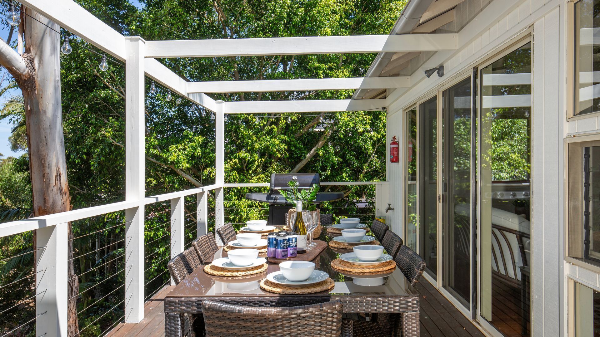 Un espace extérieur aménagé pour les repas, avec un patio couvert, un barbecue et un extincteur.