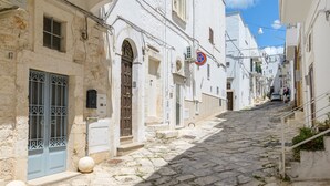 Una estrecha calle adoquinada bordeada por edificios blancos con puertas arqueadas y un letrero de no estacionamiento.