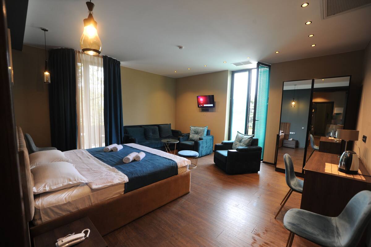 A hotel room with a bed, a sofa, a desk, and a TV.