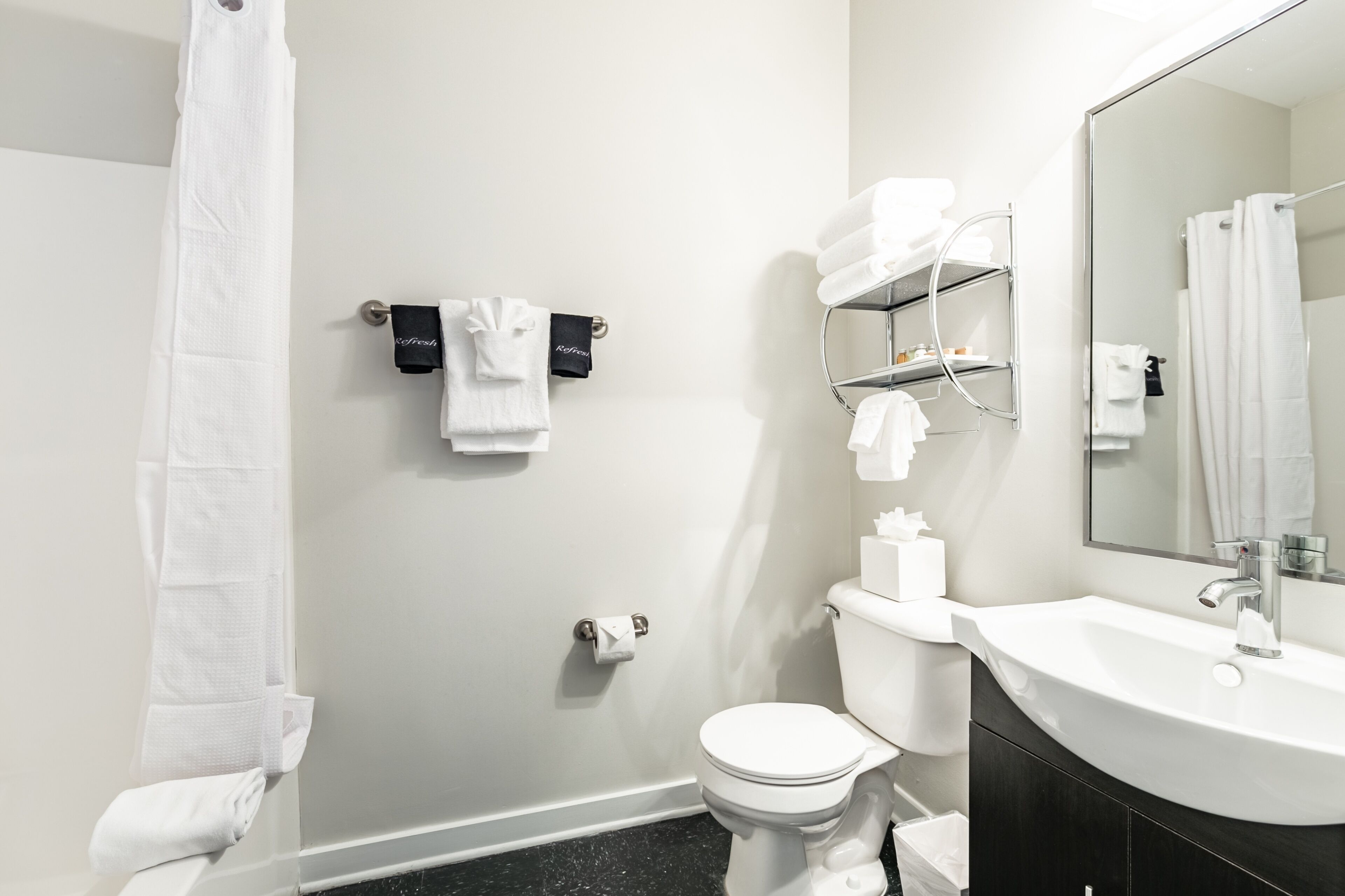 Et badeværelse med toilet, vask og et håndklædetørrestativ med håndklæder.