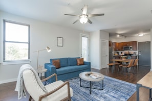 A modern living room with a blue sofa, a round coffee table, and a ceiling fan. - CozySuites Music Row (Nashville)