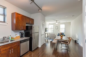 Una cocina moderna con electrodomésticos de acero inoxidable, armarios de madera y un comedor con mesa y sillas.