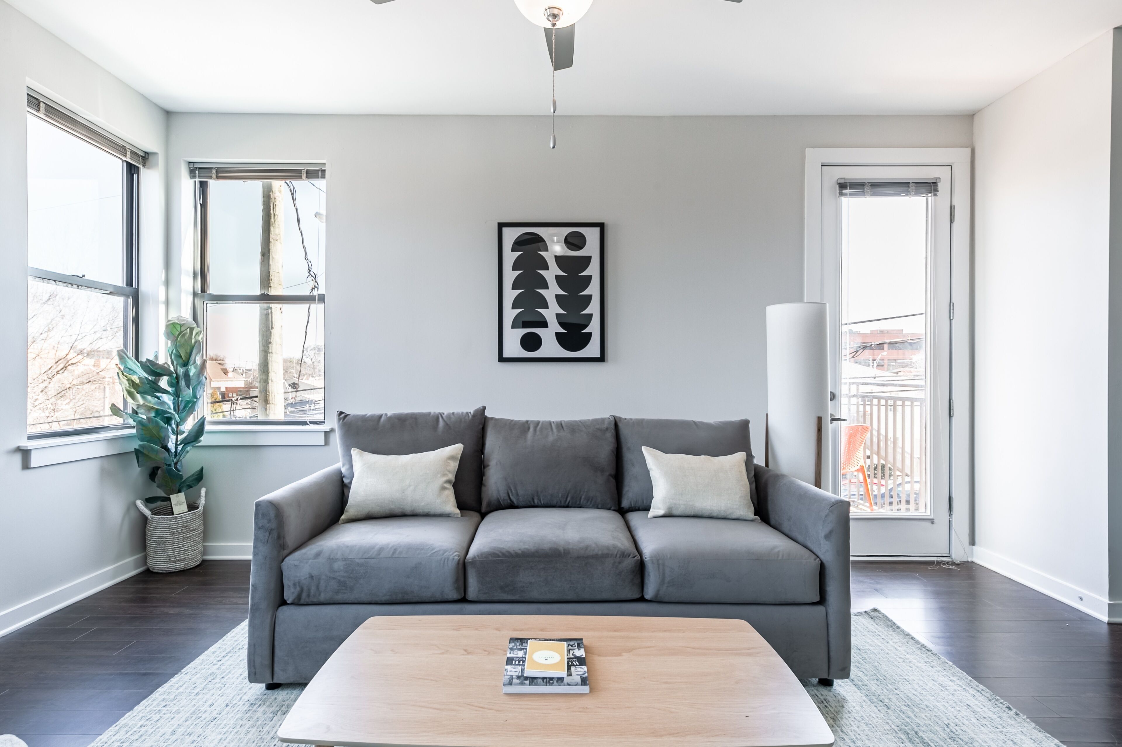 Una sala moderna con un sofá gris, una mesa de centro y una obra de arte abstracta enmarcada en la pared.