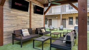 An outdoor seating area with sofas and tables, a ceiling fan, and a sign for 'COZY SUITES'. - CozySuites Music Row (Nashville)