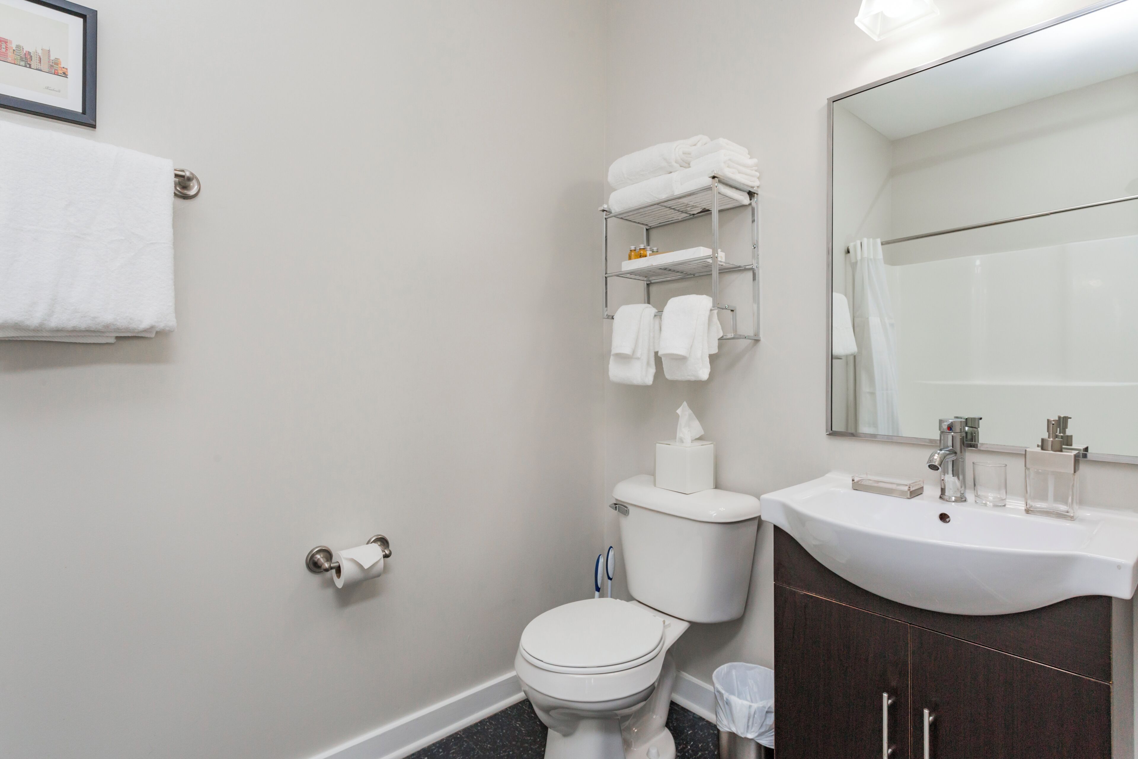 A bathroom with a toilet, sink, and a mirror.