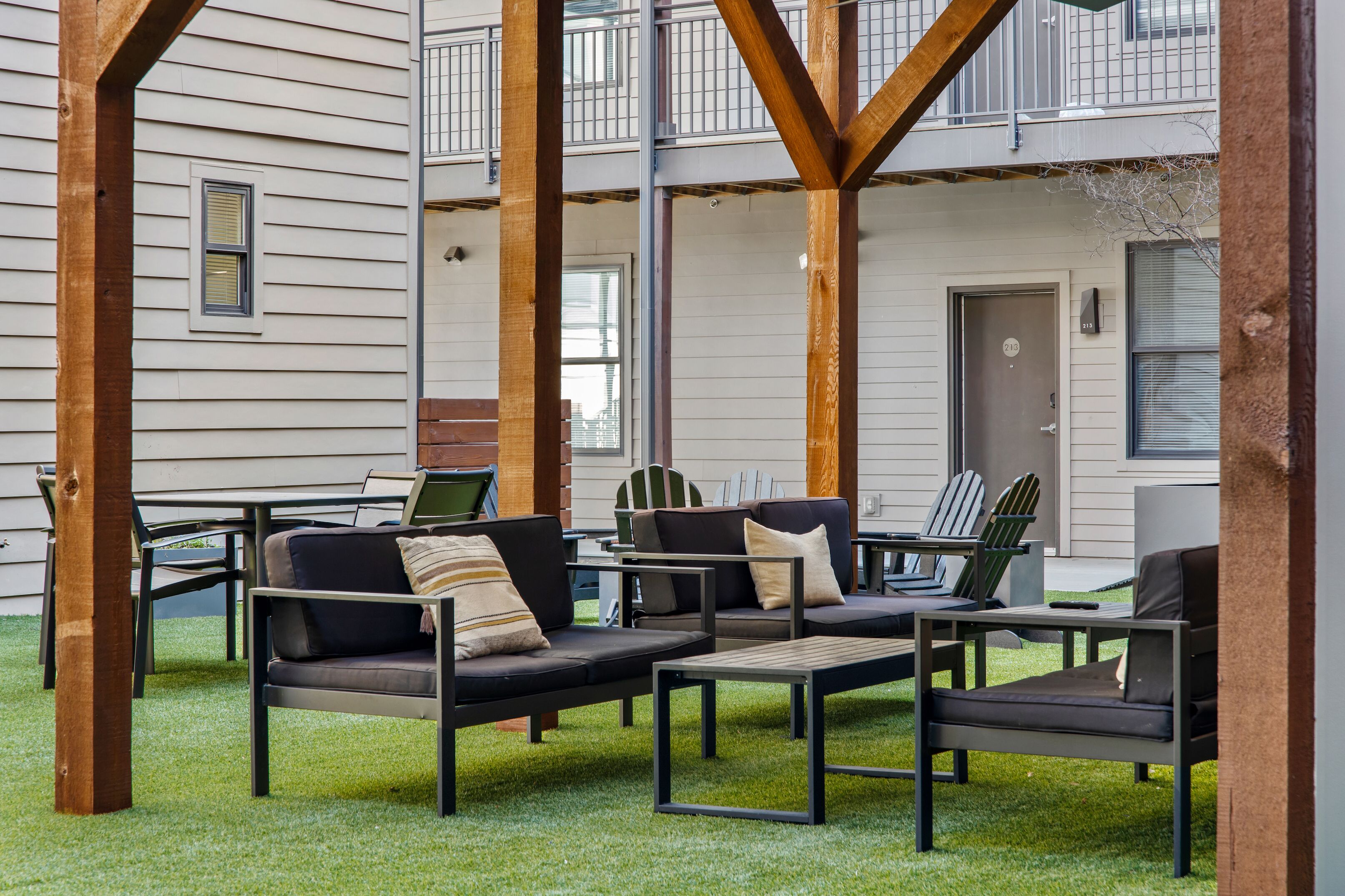 An outdoor seating area with a sofa and chairs, a table, and a view of a building with a balcony.