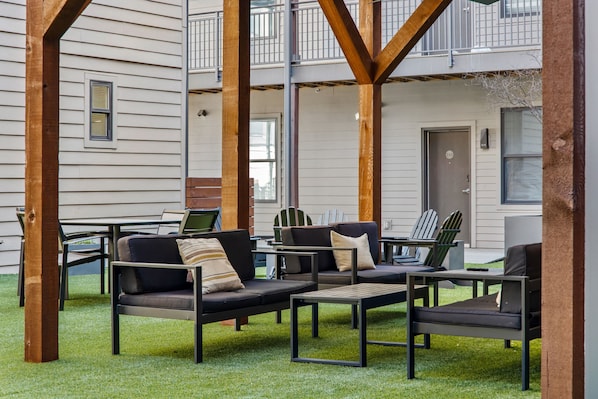 An outdoor seating area with a sofa and chairs, a table, and a view of a building with a balcony. - CozySuites Music Row (Nashville)