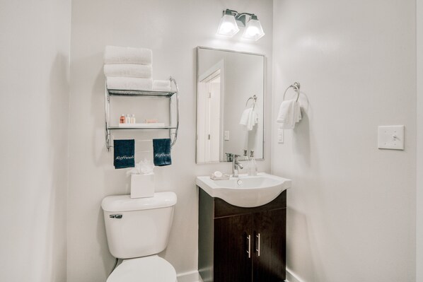 A bathroom with a toilet, a sink, a mirror, and a towel rack.