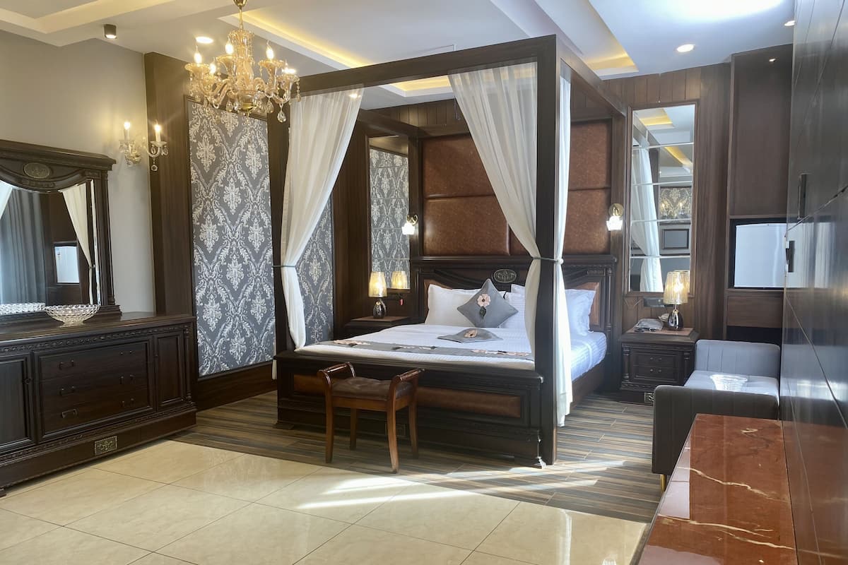 A four-poster canopy bed with a nightstand, a mirror, and a seating area with a table.
