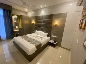 Een moderne hotelkamer met een groot bed, een nachtkastje met telefoon en een wandlamp.