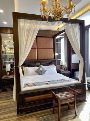 Een luxe slaapkamer met een hemelbed, een kroonluchter en een houten vloer.