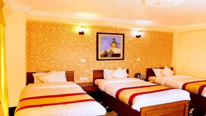 A hotel room with three single beds, each with a red and white bedspread. The room has a patterned wallpaper and a framed picture on the wall. - MeroStay 195  Hotel Garden  Pvt Ltd (Kathmandu)