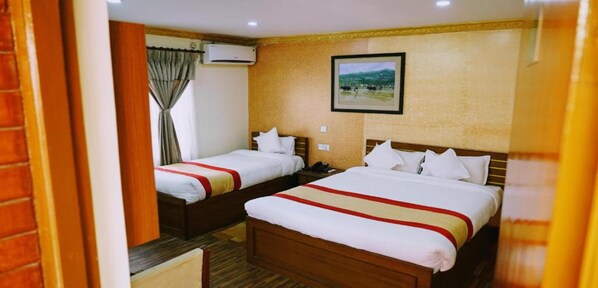 A hotel room with two beds, a wooden headboard, a mounted picture, and an air conditioning unit. - MeroStay 195  Hotel Garden  Pvt Ltd (Kathmandu)