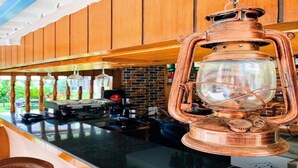 A kitchen with wooden cabinets, a copper lantern, and a coffee machine. - MeroStay 195  Hotel Garden  Pvt Ltd (Kathmandu)