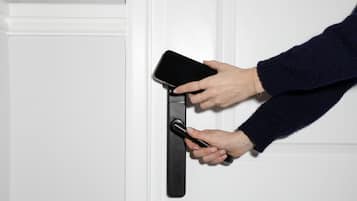 Eine Hand benutzt ein Smartphone, um eine Tür zu öffnen.