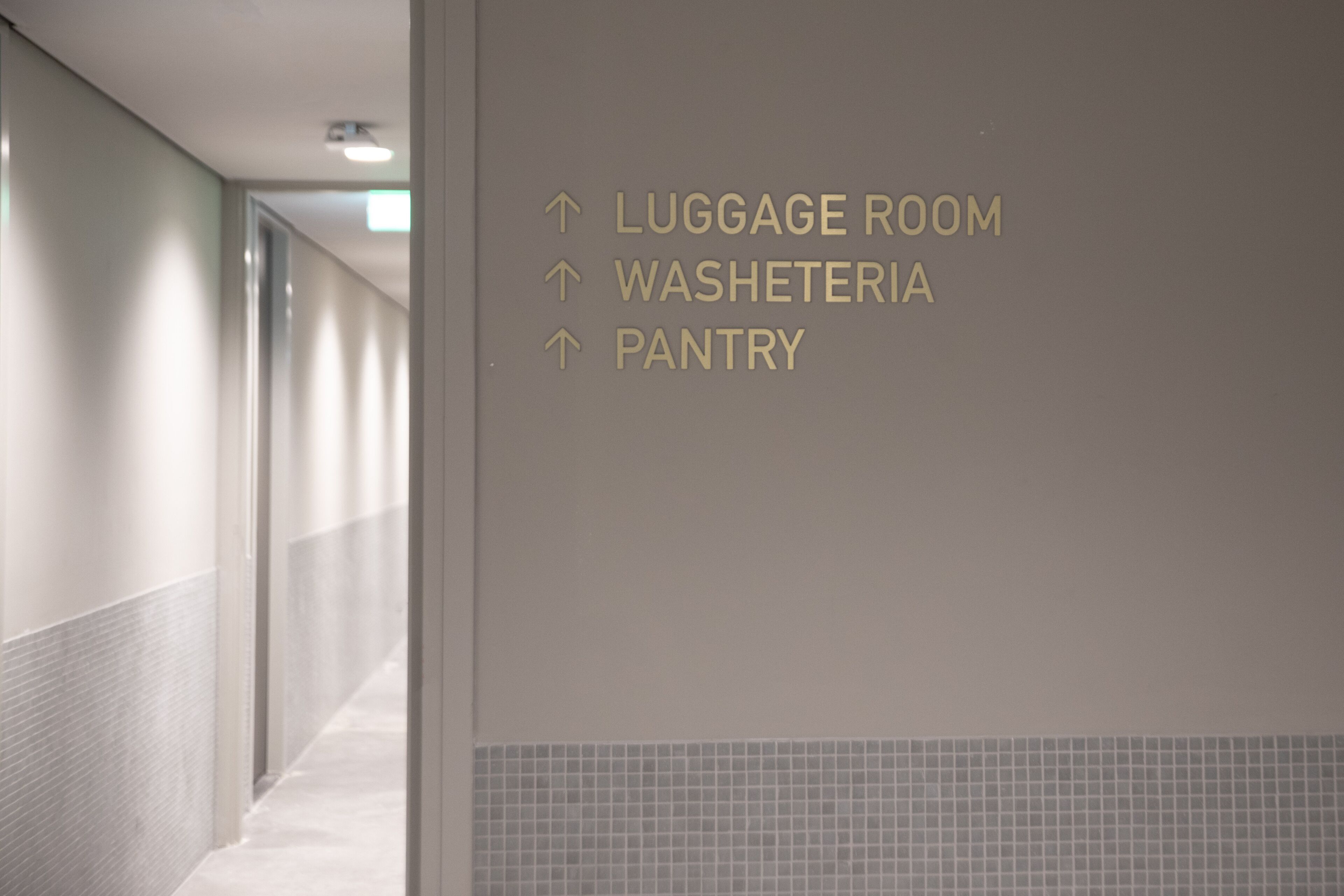 A hallway with directional signs pointing to the Luggage Room, Washateria, and Pantry.