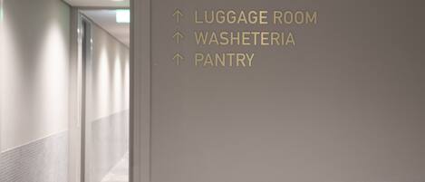 A hallway with directional signs pointing to the Luggage Room, Washateria, and Pantry.