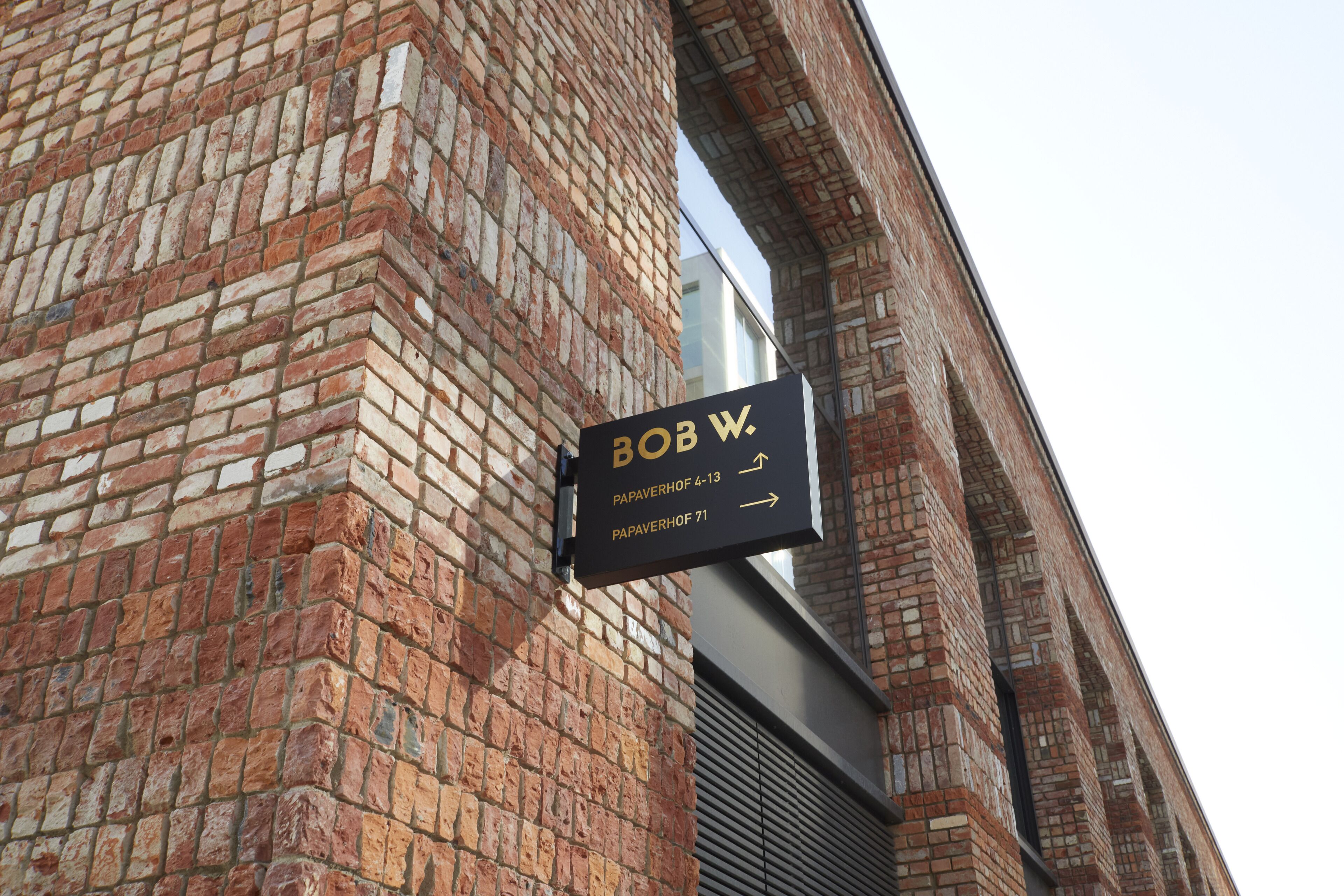 A brick building with a sign indicating 'Bob W.' and directions to 'Papaverhof 4-13' and 'Papaverhof 71'.