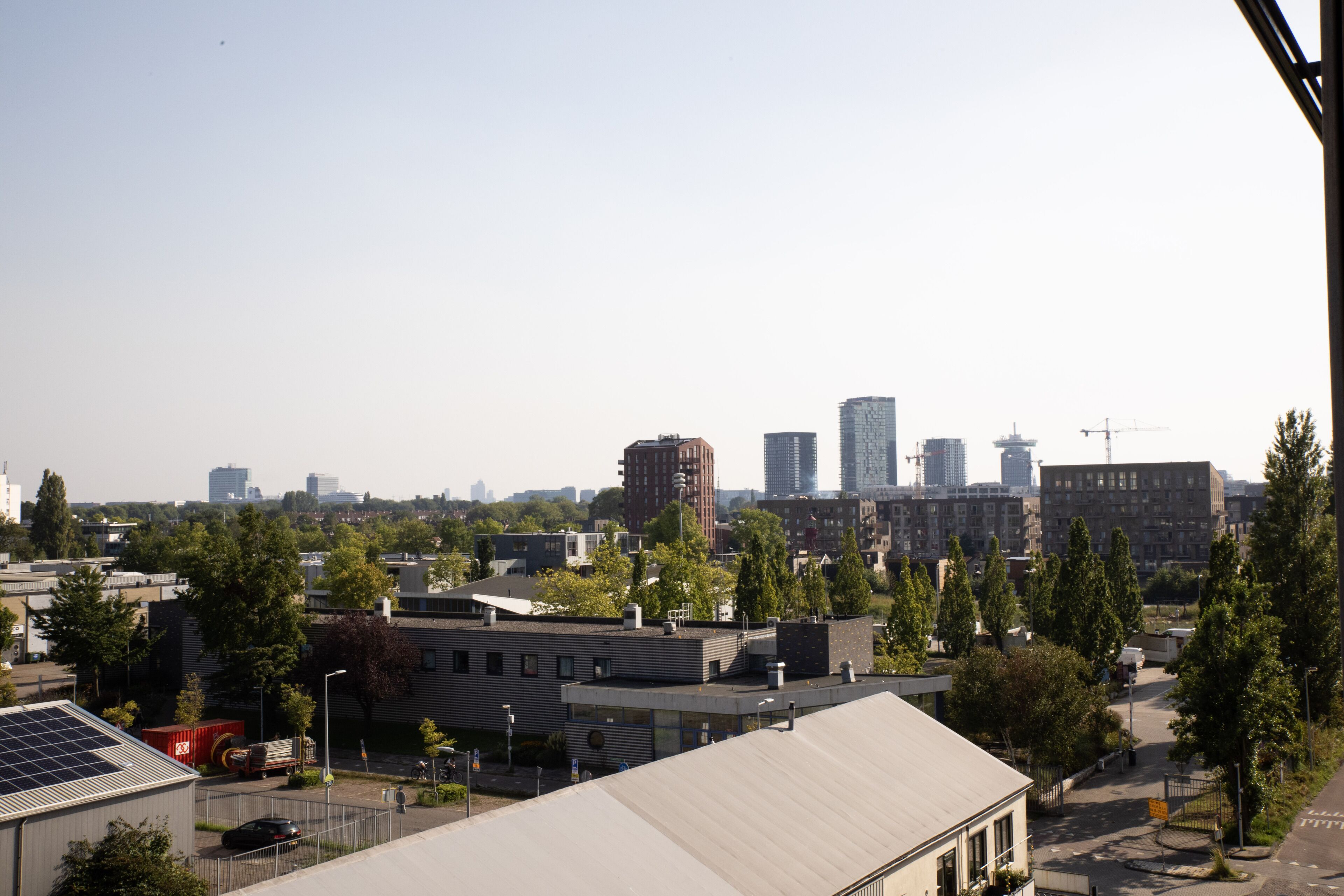A cityscape with modern buildings, a parking area, and a few trees.