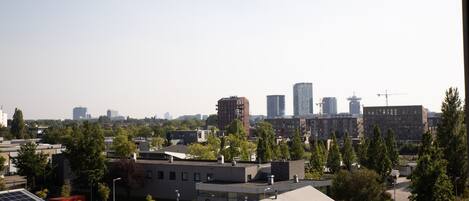 A cityscape with modern buildings, a parking area, and a few trees.