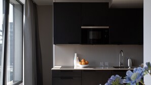 A modern kitchen with dark cabinets, a stainless steel sink, and a window with curtains. - Bob W Amsterdam Noord (Amsterdam)
