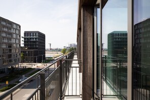 Un edificio moderno con amplios ventanales y un balcón con vistas a un paisaje urbano.