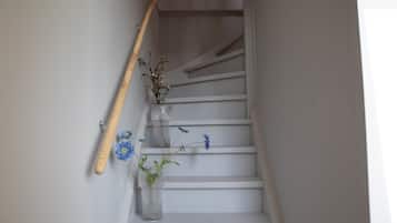 Un escalier avec une rampe en bois et un vase rempli de fleurs.