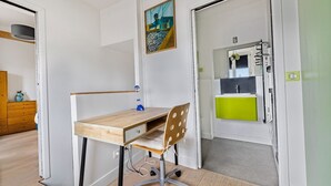 Ein Zimmer mit Holzschreibtisch, einem Stuhl, einem Gemälde und einer Küchenzeile.