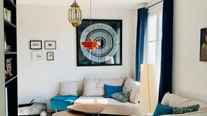 Ein modernes Wohnzimmer mit einer Couch, Sesseln, einem Couchtisch und einem Bücherregal.