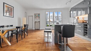 Et moderne køkken med spiseplads, trægulv og udsigt til bygninger.