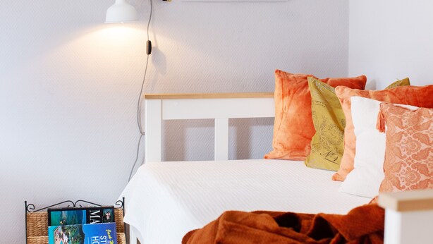 A neatly made bed with a white headboard, a lamp on the wall, and a framed picture above it. - Mediterranean design apartment I Central with cathedral view (Bremen)