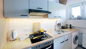 A modern kitchen with a stove, sink, and washing machine. - Mediterranean design apartment I Central with cathedral view (Bremen)