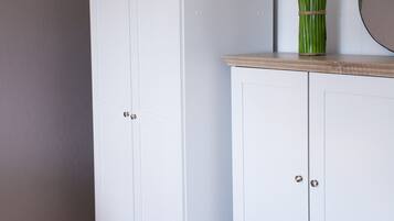Ein weißer Kleiderschrank mit Holzauszug und einem Spiegel darüber.